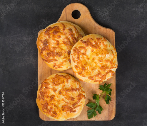 Georgian khachapuri. Cheese pie. On a wooden board. Dark background. Top view