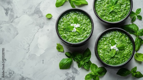 Fresh green soup served in bowls with mint and cucumber slices on a marble su...