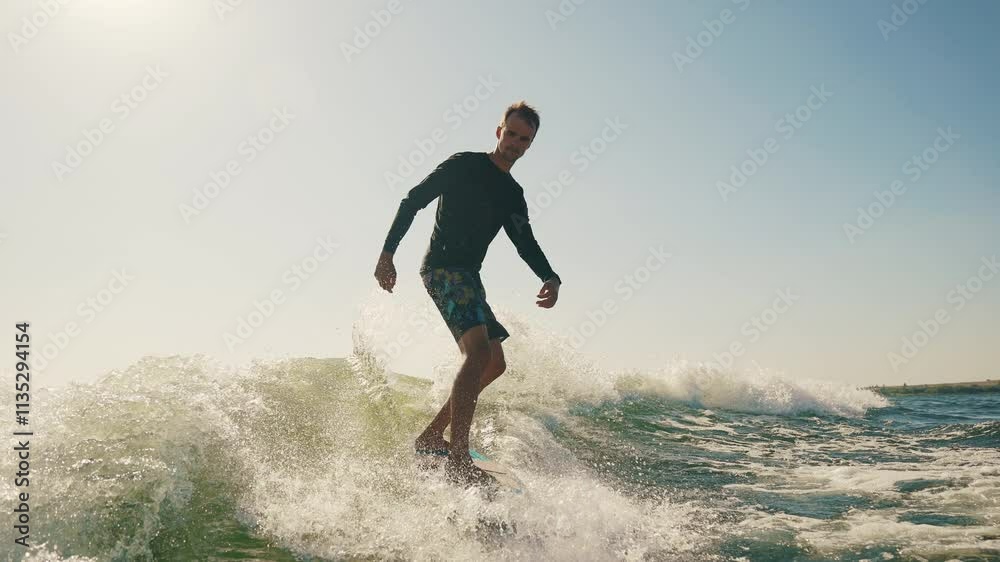 A wakeboarder performs exciting tricks on his board, moving quickly through the water. The footage shows smooth turns, jumps and acrobatics, highlighting the athlete's skill and endurance. Ideal for t A wakeboarder performs exciting tricks on his board, moving quickly through the water. The footage shows smooth turns, jumps and acrobatics, highlighting the athlete's skill and endurance. Ideal for t