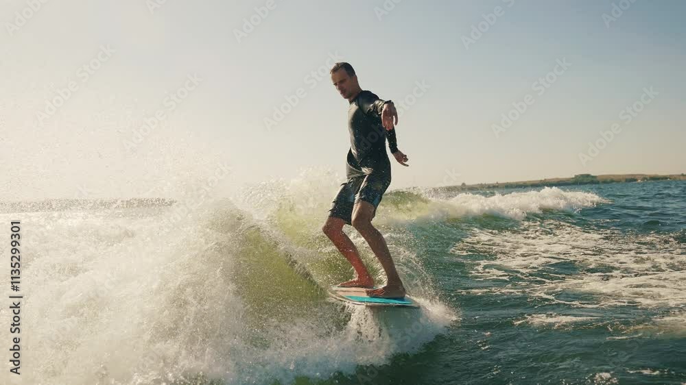 A wakeboarder performs exciting tricks on his board, moving quickly through the water. The footage shows smooth turns, jumps and acrobatics, highlighting the athlete's skill and endurance. Ideal for t A wakeboarder performs exciting tricks on his board, moving quickly through the water. The footage shows smooth turns, jumps and acrobatics, highlighting the athlete's skill and endurance. Ideal for t