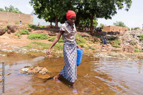 Young African girl crossing a flooded road after heavy rains; concept of climate change in third world