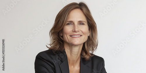  Professional mid-adult businesswoman with short hair smiling confidently against a plain white background, wearing a patterned blazer.