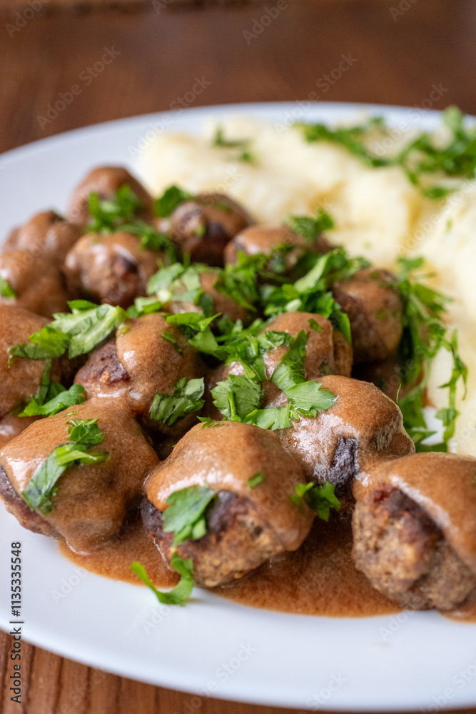 Swedish Meatballs with Gravy Sauce on a plate with mashed potatoes on a wooden background Swedish Meatballs with Gravy Sauce on a plate with mashed potatoes on a wooden background