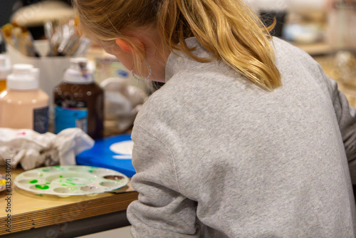 Young Girl Focused on Painting in Art Class Workshop with Brushes and Palette on Table