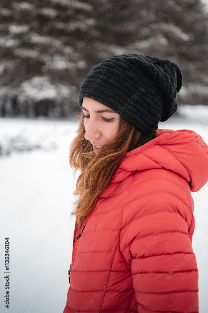It is winter, and a girl in a black hat looks down in a snowy forest in Alava, Euskadi It is winter, and a girl in a black hat looks down in a snowy forest in Alava, Euskadi