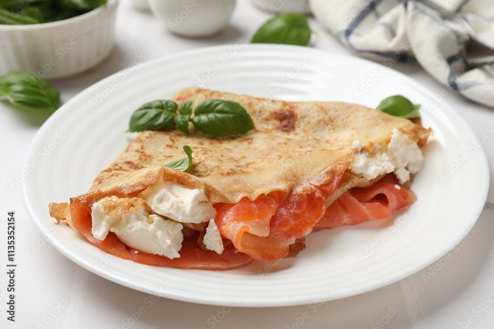 Delicious crepe with salmon, cream cheese and basil on white table, closeup Delicious crepe with salmon, cream cheese and basil on white table, closeup