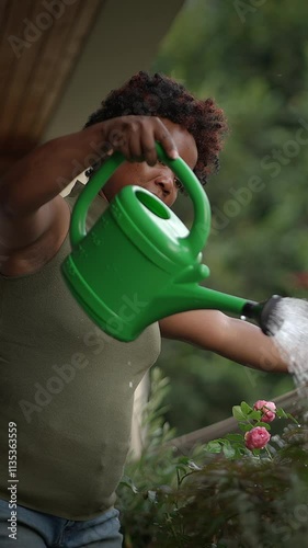 A woman waters plants in a greenhouse, showcasing her love for home gardening amidst nature