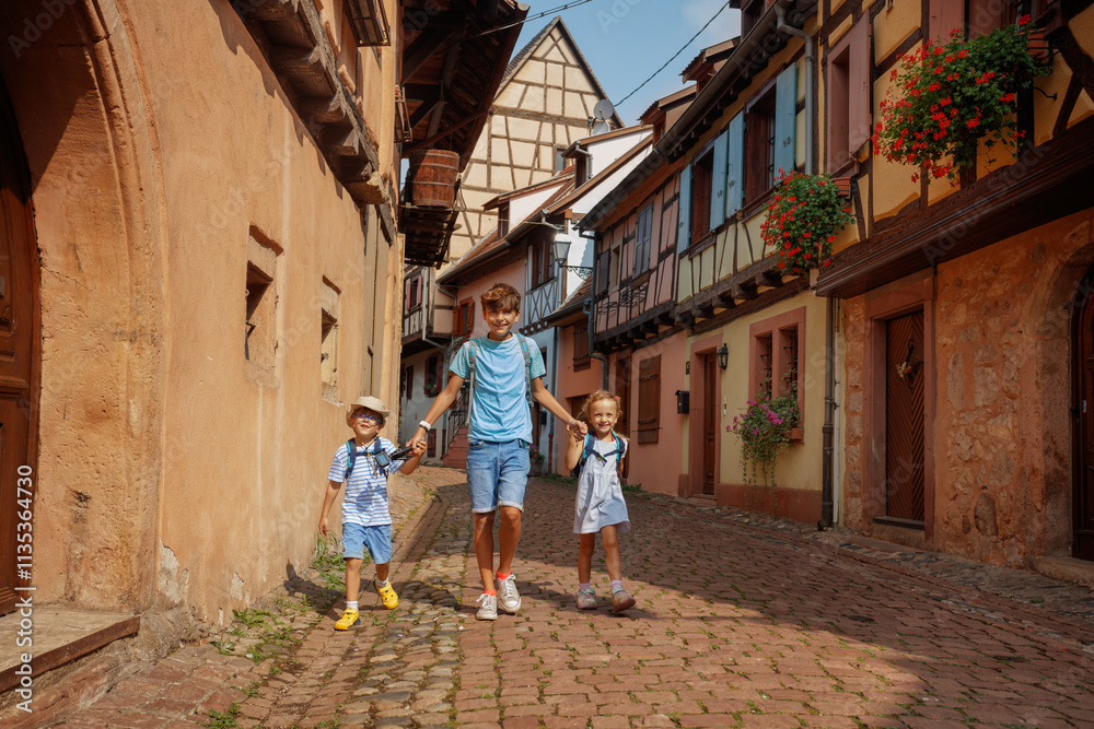 Three children walk in a picturesque old town alley at Eguisheim Three children walk in a picturesque old town alley at Eguisheim