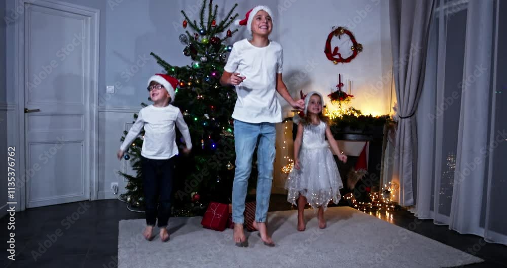 Kids siblings jump joyfully beside a twinkling Christmas tree Kids siblings jump joyfully beside a twinkling Christmas tree