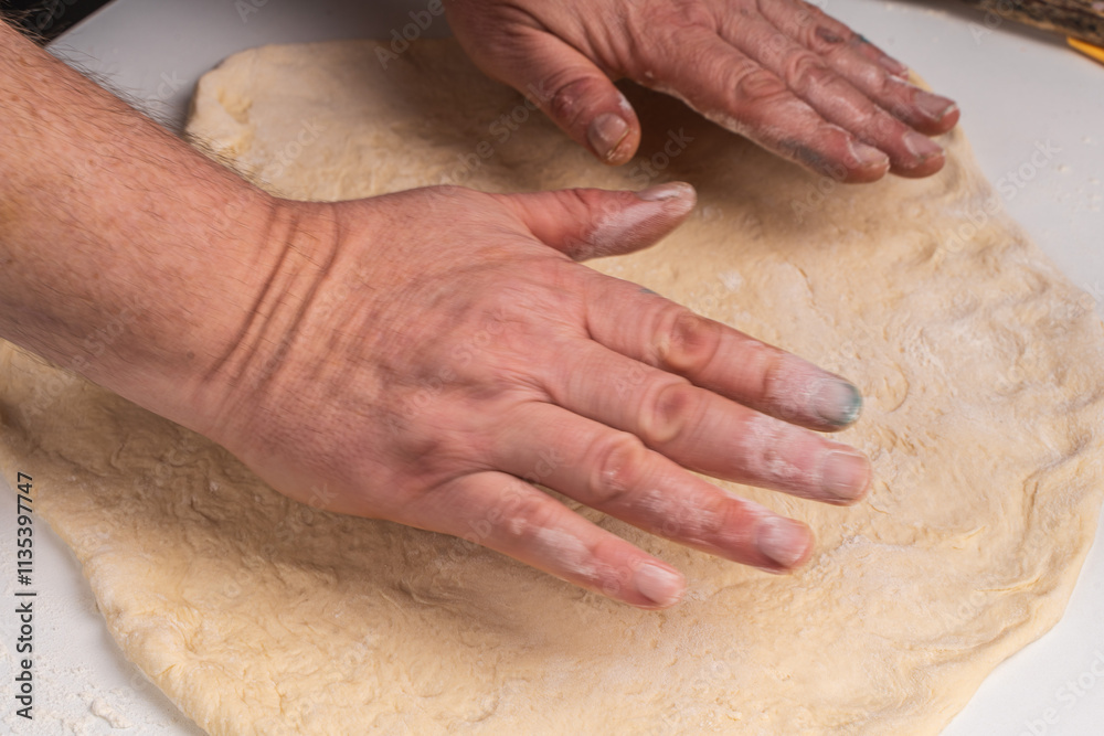 Men's hands stretching yeast pizza dough on a white table. The process of making a pizza or pie. Men's hands stretching yeast pizza dough on a white table. The process of making a pizza or pie.