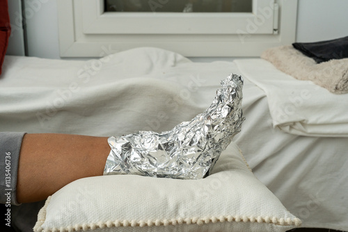 Foot Wrapped in Aluminum Foil Resting on a Pillow