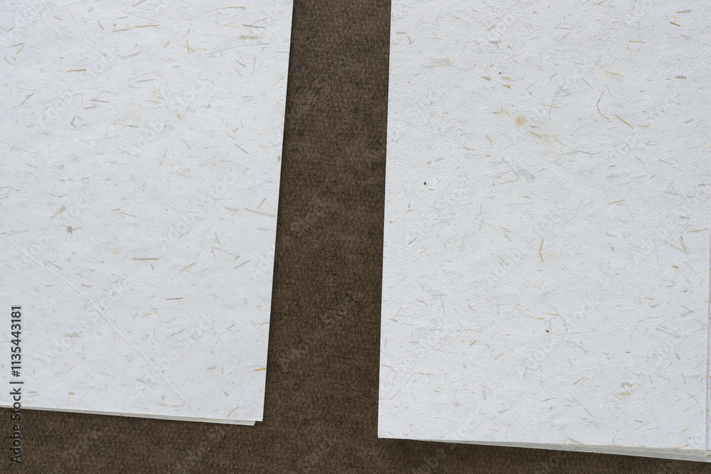 Fototapeta premium two piles of textured paper with natural elements on brown board