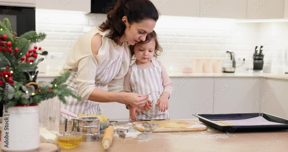mother and little child daughter cut out various shapes of Christmas cookies in kitchen. mother and little child daughter cut out various shapes of Christmas cookies in kitchen.