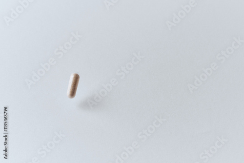 One medicinal calsule falling down in the air pharmaceutical concept