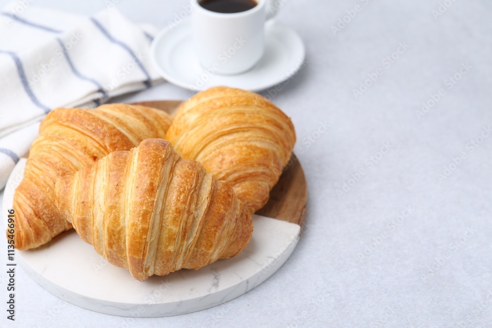Tasty fresh croissants and cup of coffee on light table, closeup. Space for text Tasty fresh croissants and cup of coffee on light table, closeup. Space for text