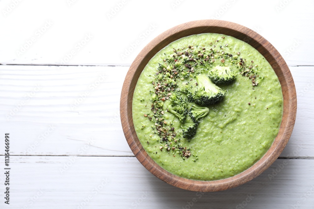Delicious broccoli cream soup in bowl on white wooden table, top view. Space for text Delicious broccoli cream soup in bowl on white wooden table, top view. Space for text