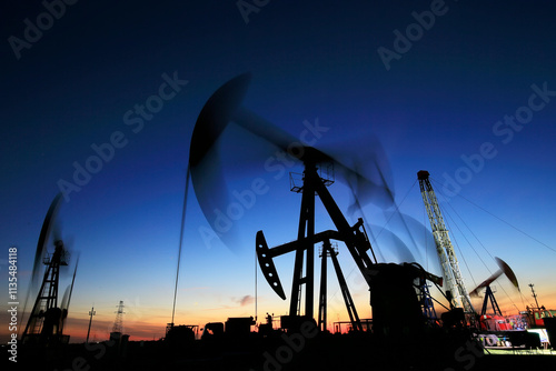 Oil field site, in the evening, oil pumps are running, photo