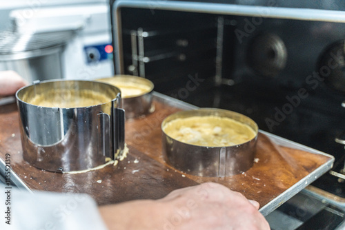 Pie making process. Raw apple tarts or pies in baking molds on a baking sheet are put by the confectioner's hands into a steam convection oven. Confectionery or production workshop. High quality photo