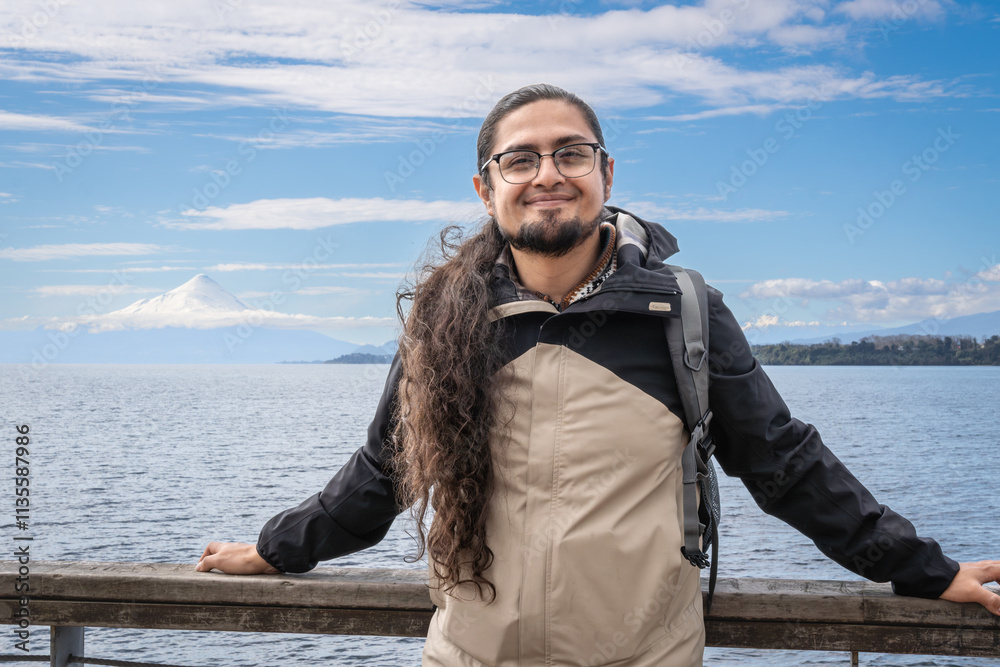Puerto Varas, Los Lagos, Chile. Young male traveler - tourist beside the snow-capped volcano Osorno and Lake Llanquihue as seen from the city of Puerto Varas in Chilean Patagonia. Puerto Varas, Los Lagos, Chile. Young male traveler - tourist beside the snow-capped volcano Osorno and Lake Llanquihue as seen from the city of Puerto Varas in Chilean Patagonia.