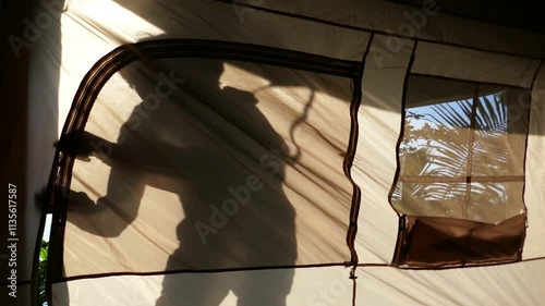 a man opens the door of a camping tent and enters