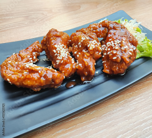 Korean style spicy fried chicken wings served with signature gochujang sauce, the perfect mix of spicy, sweet and slightly sour flavors. Tender and juicy chicken meat coated with crispy flour. photo