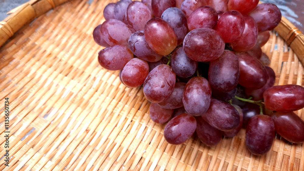 Blurred image of purple grapes on a bamboo basket Blurred image of purple grapes on a bamboo basket
