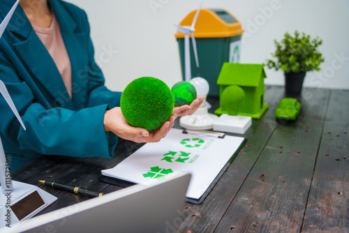 A businesswoman sits at a desk discussing the Earth, environment, renewable energy, and sustainability, with a power sled, trash can, and wind turbine symbolizing eco-friendly and green initiatives photo