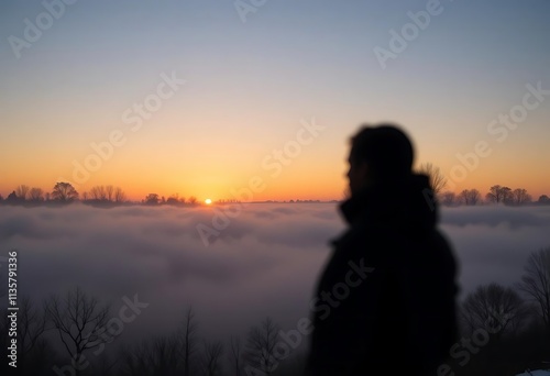 A silhouette of a sunrise breaking through winter fog 