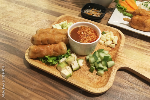 Vietnamese food name Nam Nueng wih grilled pork ball and mixed fresh vegetables and herbs with sweet and sour source in square wooden plate on wooden table. photo