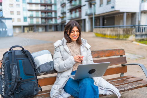 Woman using laptop sitting on a city square
