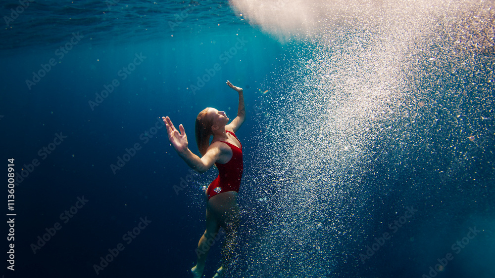 Teen girl in red suit swims underwater in the sea. Relaxed teen girl dives and swims underwater. Girl dances underwater Teen girl in red suit swims underwater in the sea. Relaxed teen girl dives and swims underwater. Girl dances underwater