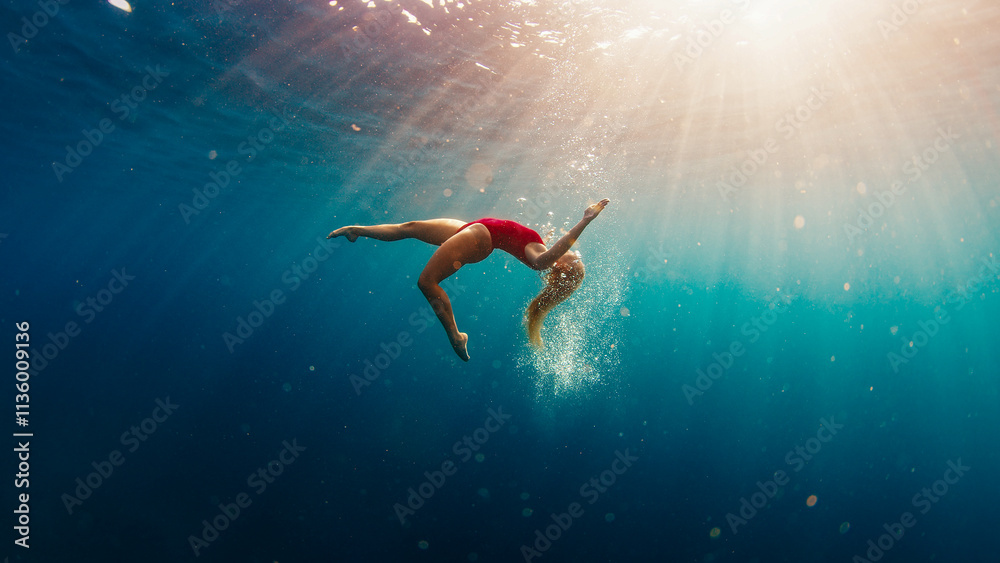 Teen girl in red suit swims underwater in the sea. Relaxed teen girl dives and swims underwater. Girl dances underwater Teen girl in red suit swims underwater in the sea. Relaxed teen girl dives and swims underwater. Girl dances underwater