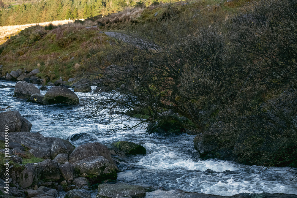 Flowing river surrounded by rocky terrain in a tranquil landscape during daytime. Flowing river surrounded by rocky terrain in a tranquil landscape during daytime.