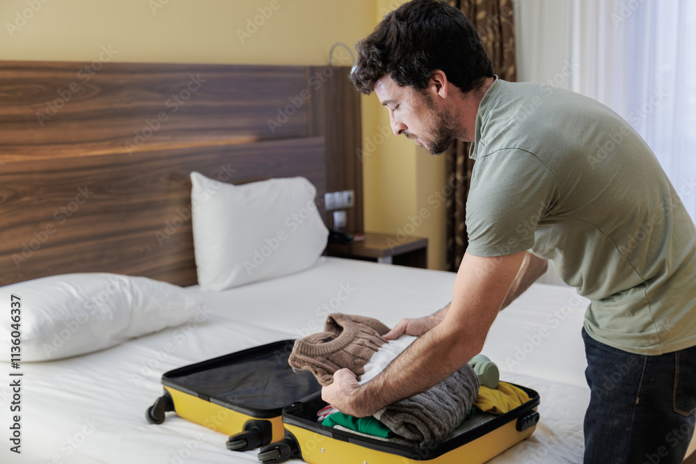 Young man putting his belongings in his suitcase to leave the hotel. The vacation or business trip is over and you return home. Young man putting his belongings in his suitcase to leave the hotel. The vacation or business trip is over and you return home.