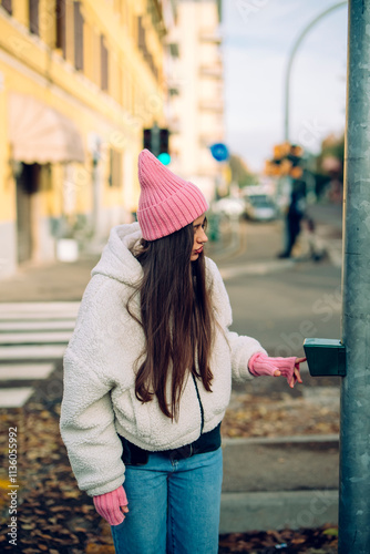 A Stylish Young Woman stands confidently at the Crosswalk within a vibrant Urban Setting