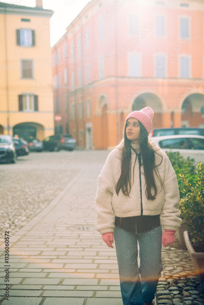 Fototapeta premium A young woman is leisurely strolling through the bustling city streets in a stylish winter outfit