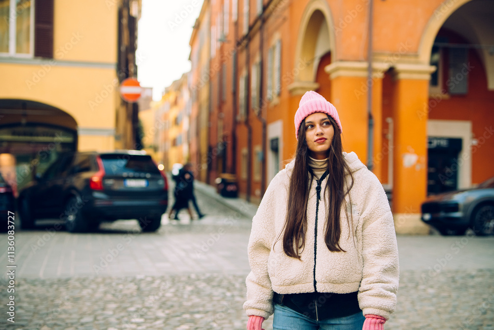 Fototapeta premium A Young Woman Dressed in a Cozy Winter Outfit Strolling Along a Charming Cobblestone Street