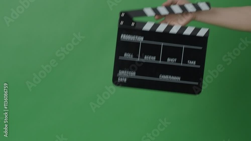 Movie Clapper board clapped by Hands on green screen camera background. Filmmaker hit film slate on green camera frame. Clapperboard Chroma key suit shooting. Green screen composite video production.