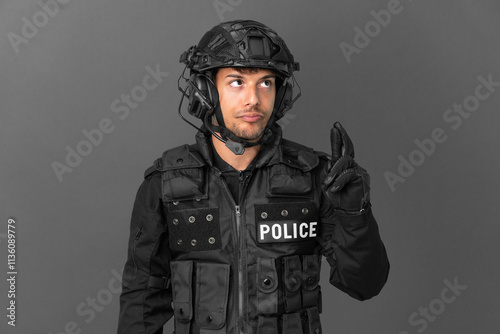 SWAT caucasian man isolated on grey background with fingers crossing and wishing the best