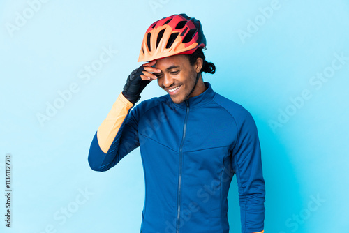 Young cyclist man with braids over isolated background laughing photo