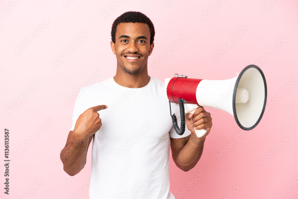 African American handsome man on isolated pink background holding a megaphone and with surprise facial expression African American handsome man on isolated pink background holding a megaphone and with surprise facial expression