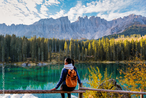 Breathtaking view of the Dolomites reflected in a serene lake at dawn with a hiker enjoying nature