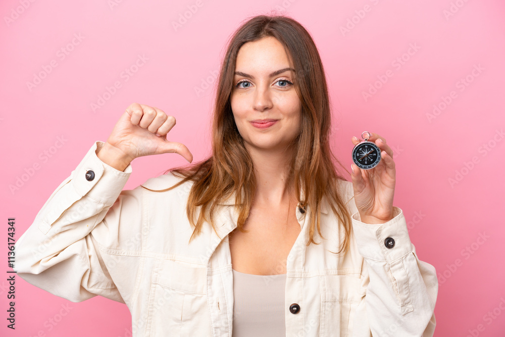 Young caucasian woman holding compass isolated on pink background proud and self-satisfied Young caucasian woman holding compass isolated on pink background proud and self-satisfied
