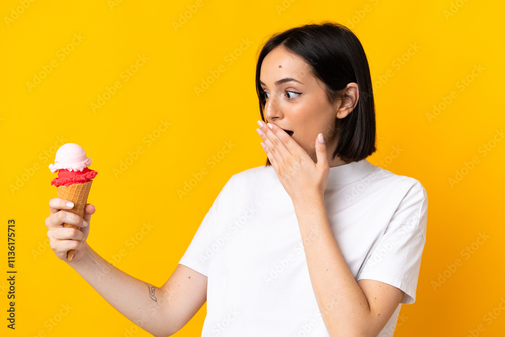 Young caucasian woman with a cornet ice cream isolated on yellow background with surprise and shocked facial expression Young caucasian woman with a cornet ice cream isolated on yellow background with surprise and shocked facial expression