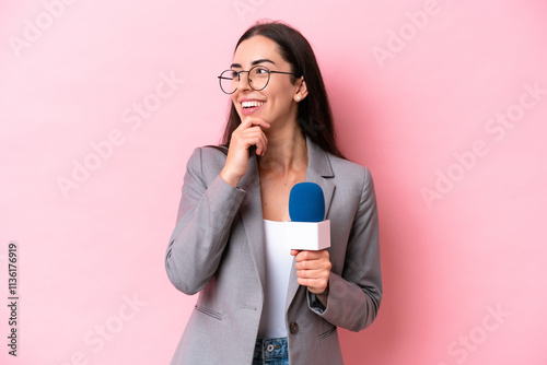 Young caucasian tv presenter woman isolated on pink background looking to the side and smiling