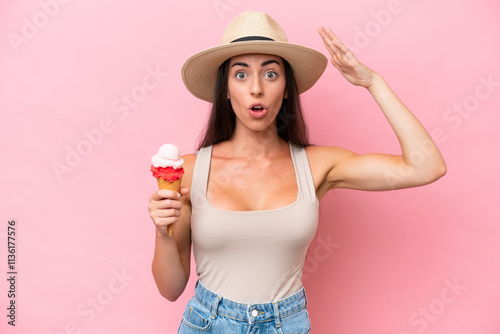 Young caucasian woman with a cornet ice cream isolated on pink background with surprise expression