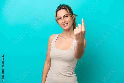 Young caucasian woman isolated on blue background doing coming gesture