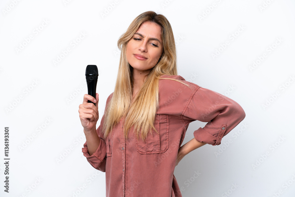Singer Uruguayan woman picking up a microphone isolated on white background suffering from backache for having made an effort Singer Uruguayan woman picking up a microphone isolated on white background suffering from backache for having made an effort