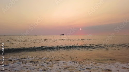 Sunset sky, tranquil waters, and a traditional boat on the horizon