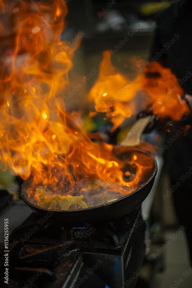 cooking steak in a restaurant kitchen with a fire in a pan cooking steak in a restaurant kitchen with a fire in a pan
